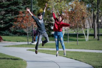 jcp_ridgewater_2017_3456 male and female student jumping on campus