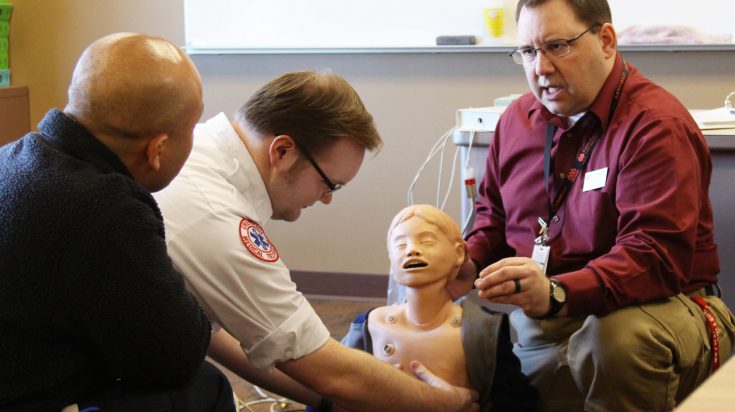 Three men skills learning on CPR mannequin