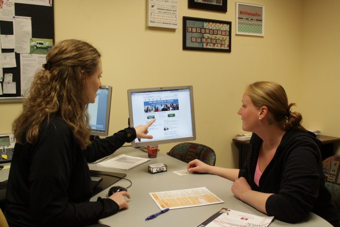 Two people meeting with a computer in the background
