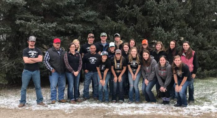 group of students posing for a picture outside in front of pine trees