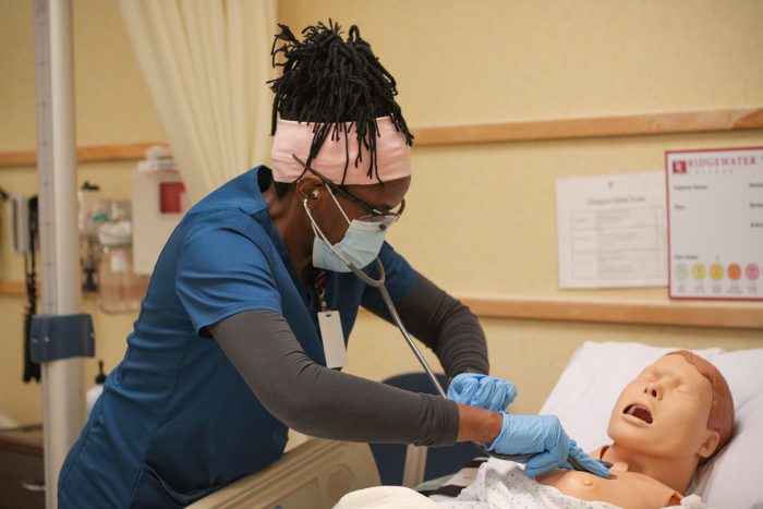 Diverse nursing student listening to patient chest