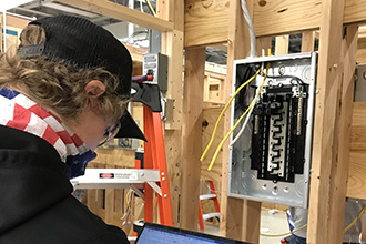 Photo of electrical student using a laptop to check their electrical setup.