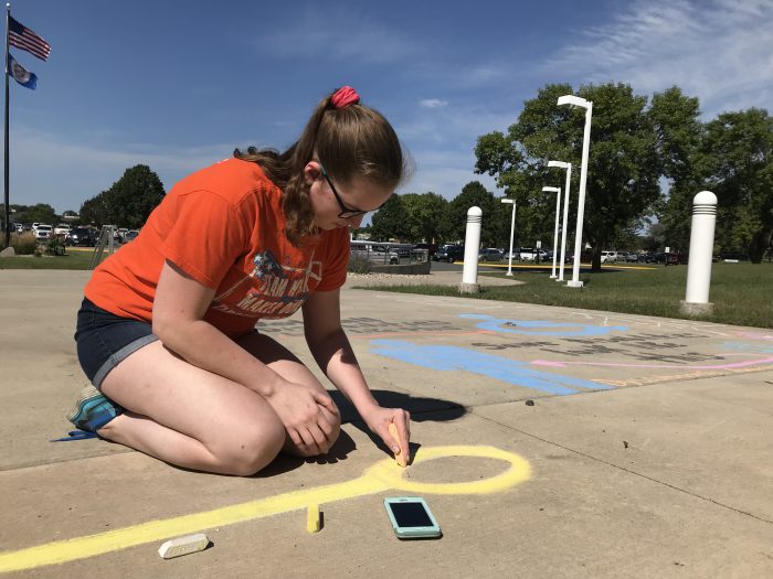 Photo of the student using chalk on the sidewalk.